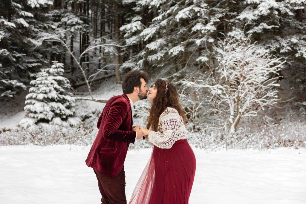 Séance photo grossesse à Payolle dans la neige en Haute-Pyrénées couple qui s'embrassent